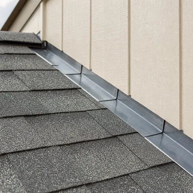 Metal flashing sealing the seam where a shingle roof meets a sided wall